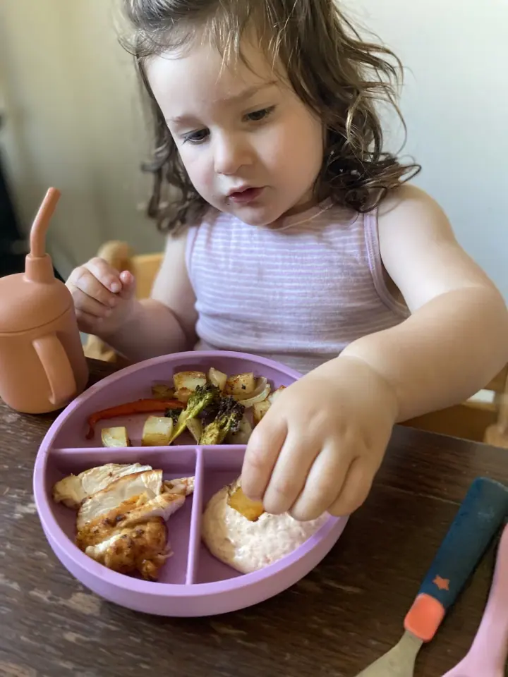 An older toddler enjoying an independent meal with the dinnerware set.