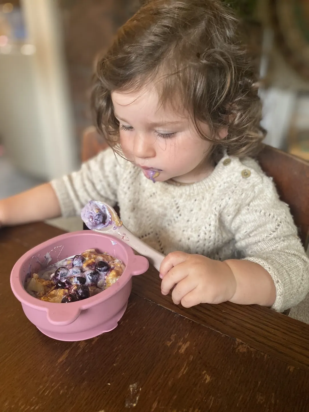 A toddler eating independently from a bowl.