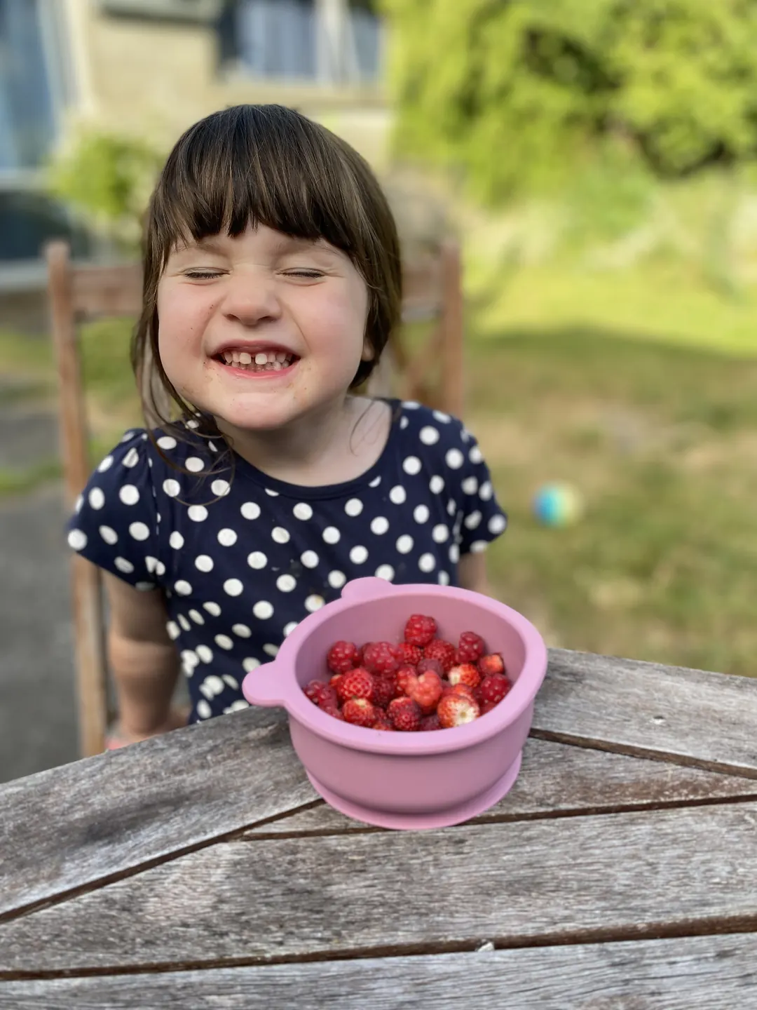An older child enjoying berries from a suction bowl outdoors.