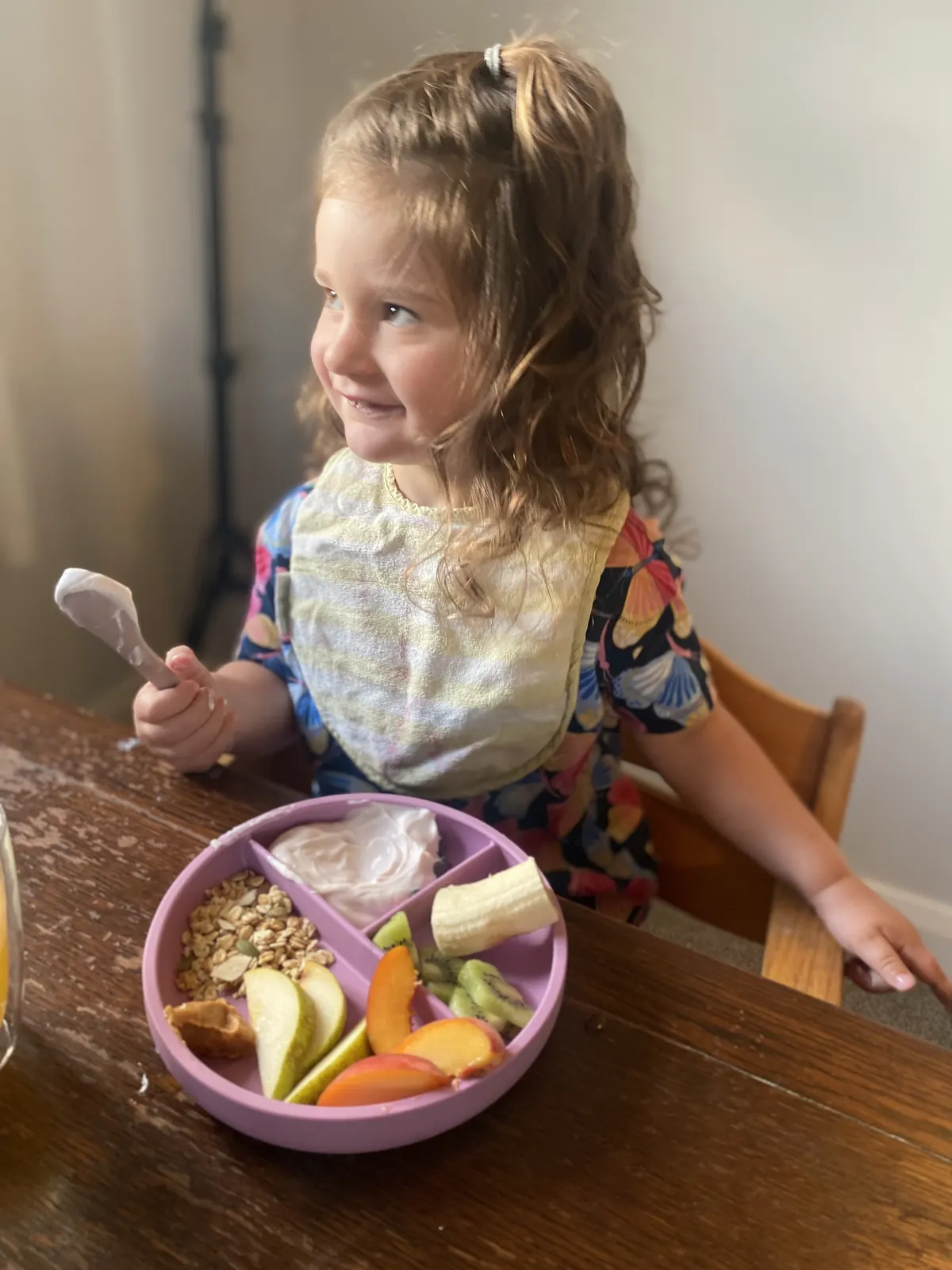 A child enjoying food from a pink divided plate.
