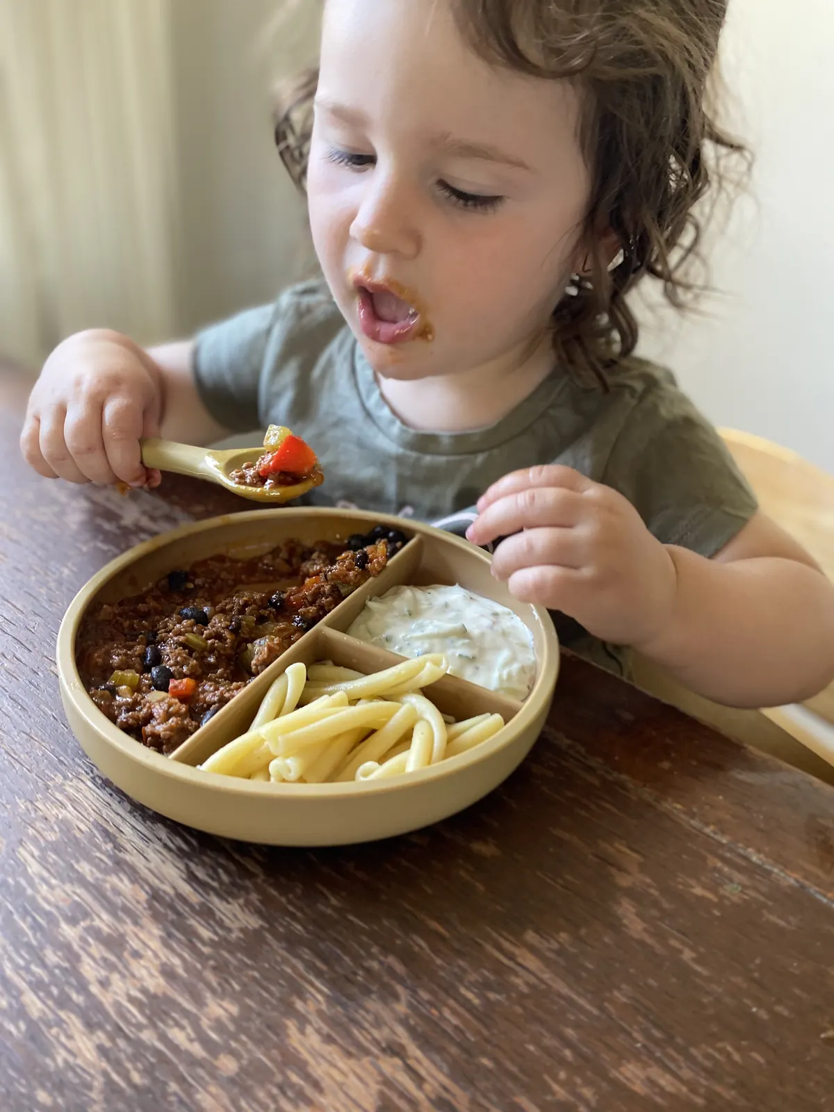 A close-up of a child using a neutral divided plate.