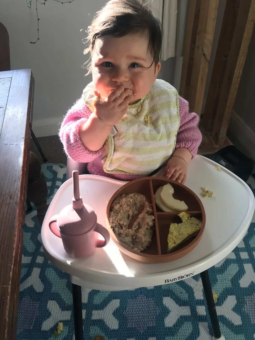 A baby using the dinnerware set at the family table.