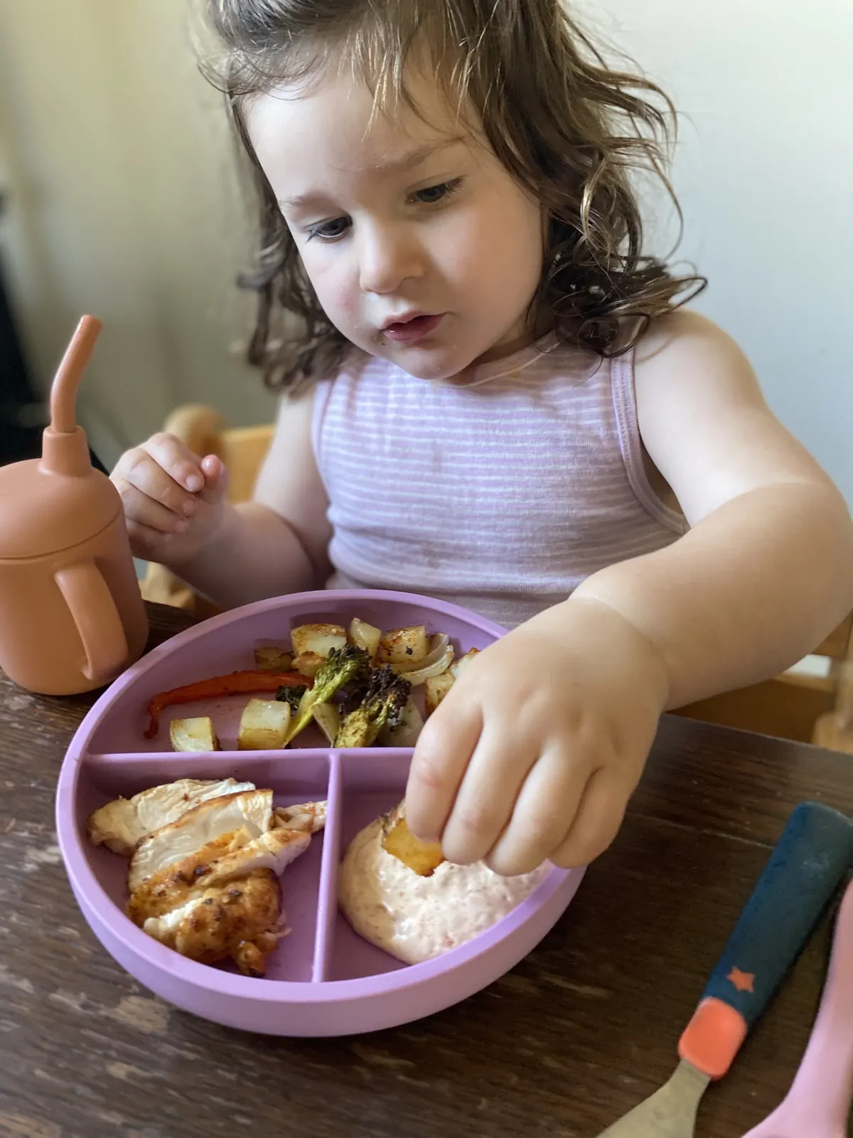 An older toddler enjoying an independent meal with the dinnerware set.