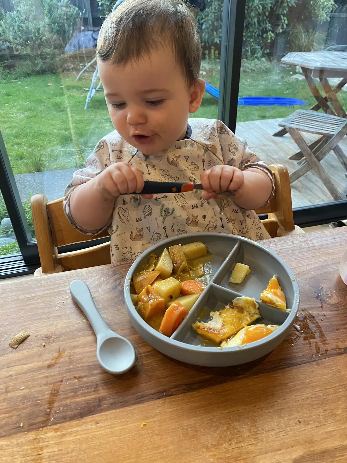 A toddler enjoying the dinnerware set beside the garden.