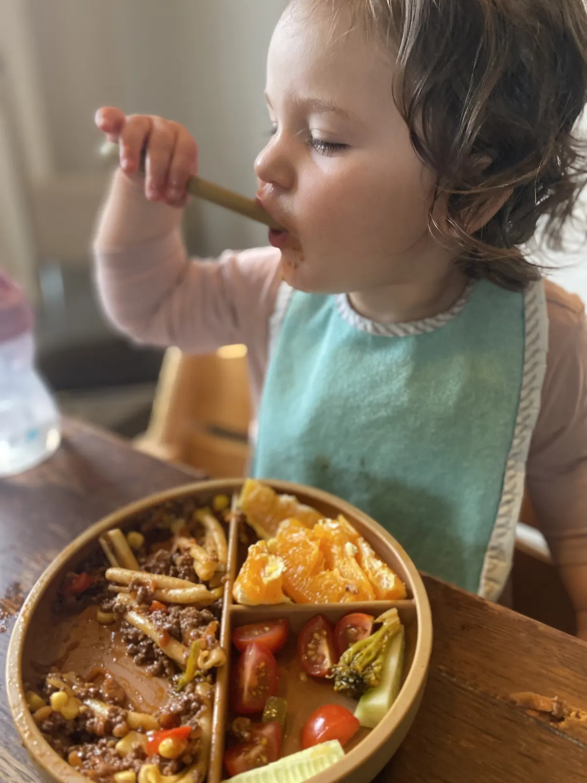 A little eater practising with the spoon and divided plate.