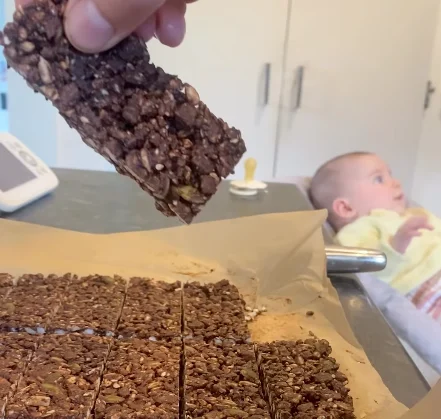 Chocolate ricecake bar held above a lined tray of sliced chocolate ricecake bars.